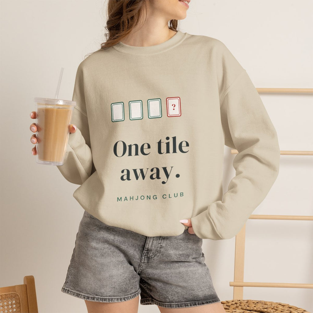 One Tile Away mahjong sweatshirt worn with iced coffee, shown in Sand