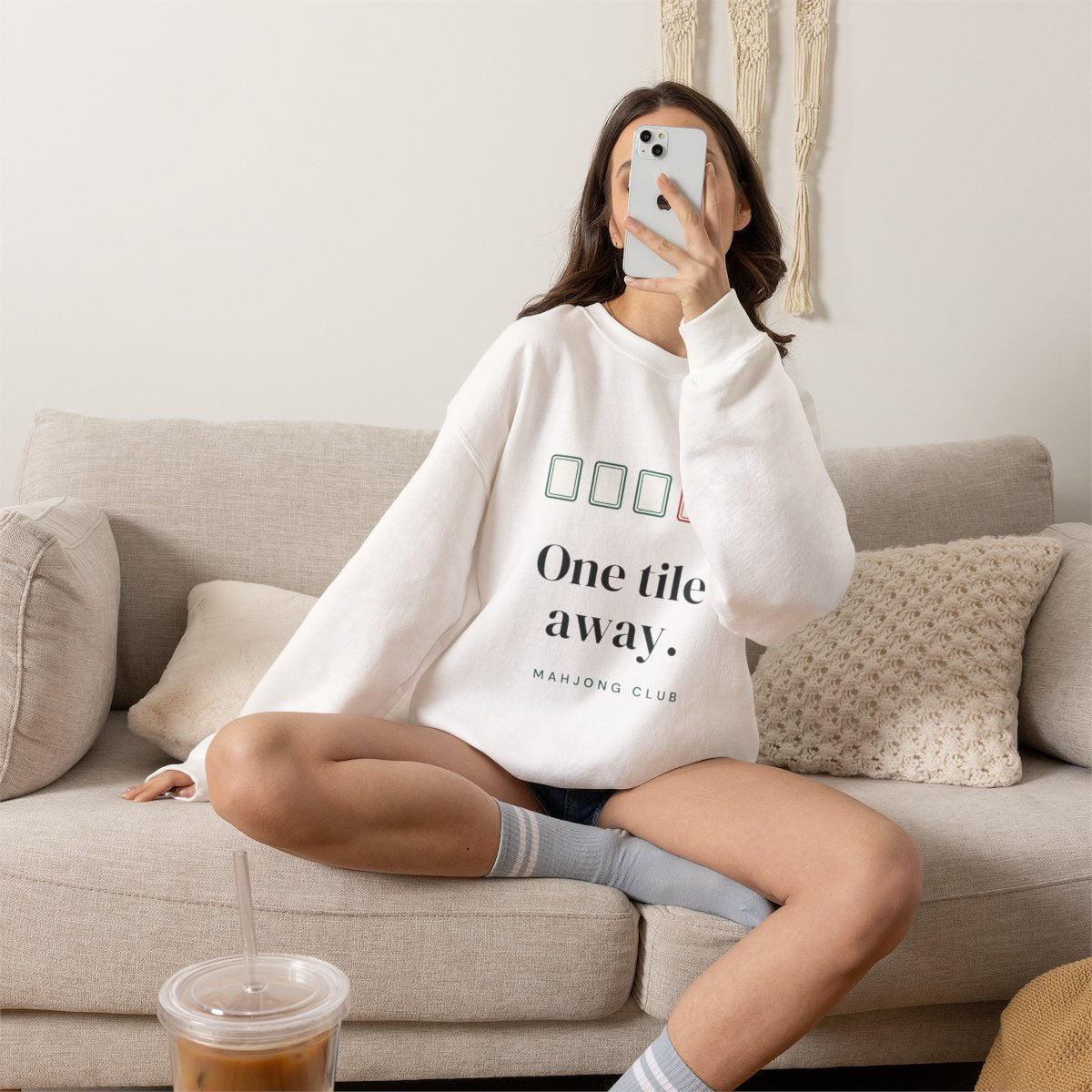 One Tile Away mahjong sweatshirt worn on the sofa, shown in White